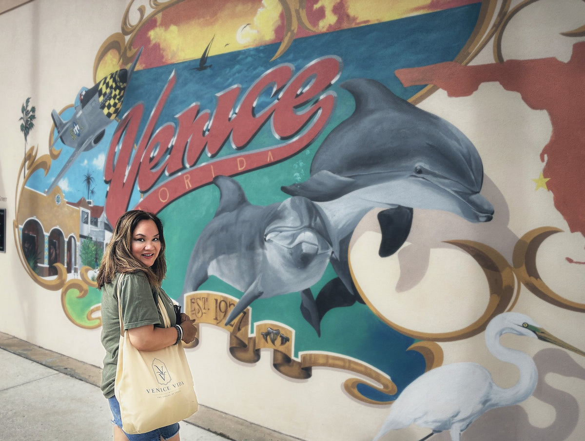 Venice Vida co-founder carrying the Venice Vida tote in front of the downtown Venice, Florida mural