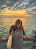 Venice Vida co-founder wearing the Evening Gulf Tee with gold VV logo on the Venice Fishing Pier at sunset over the Gulf