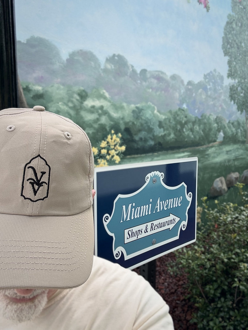 Venice Vida Heritage Hat in Khaki worn beside the Miami Avenue shops and restaurants sign in downtown Venice, Florida