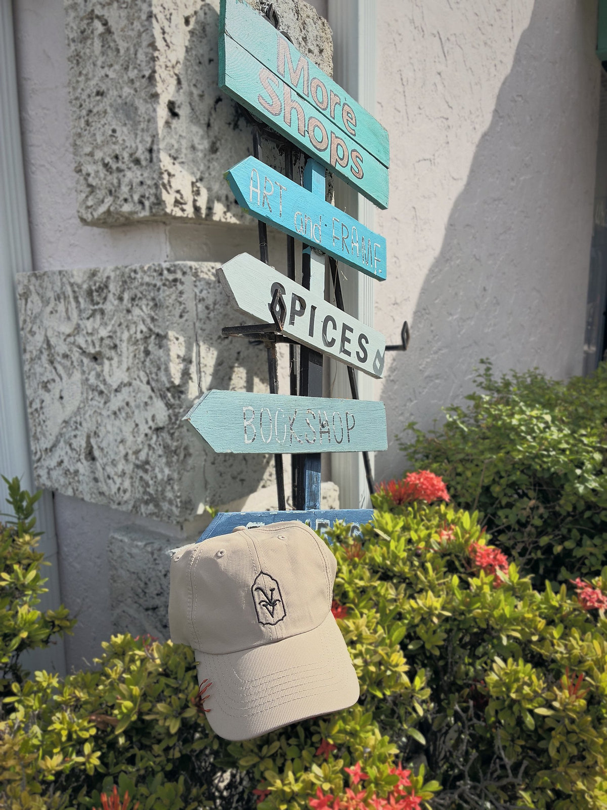 Venice Vida Heritage Hat in Khaki with black embroidered VV mark beside hand-painted shop signs in downtown Venice, Florida
