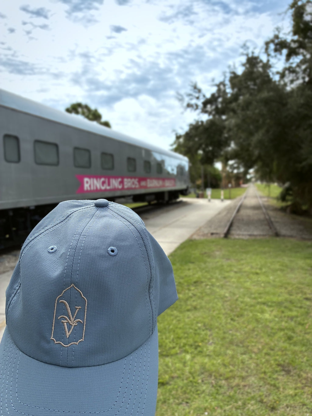 Venice Vida Signature Hat in Breaker Blue beside the historic circus train car in Venice, Florida