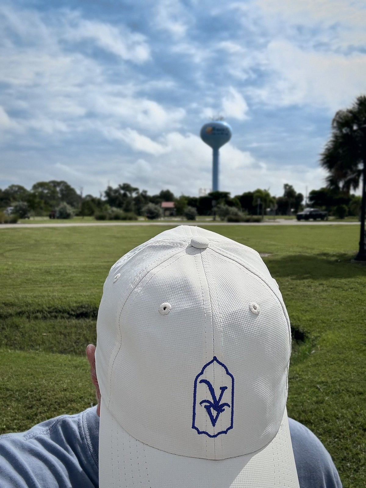 Venice Vida Whitewash Hat in Macaroon worn in a Venice, Florida park with the city water tower in the distance